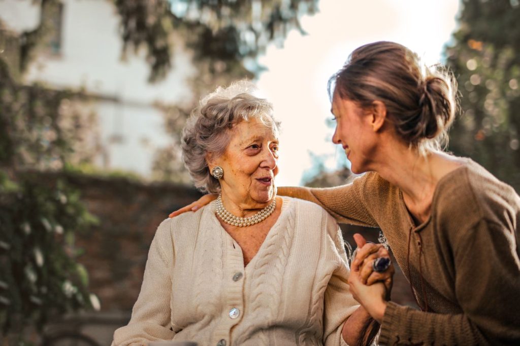 Young woman comforting smiling senior mother outdoors